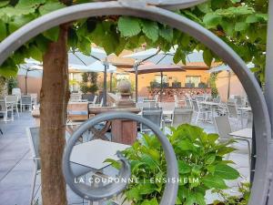 een restaurant met witte stoelen en tafels en een boom bij Hotel La Couronne in Ensisheim