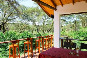 a porch with chairs and a table and a view of the forest at Enjoy the Silence, Naivasha by YourHost in Naivasha