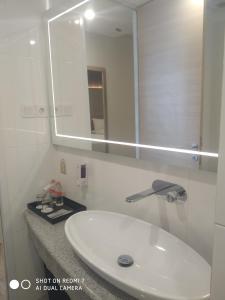 La salle de bains est pourvue d'un lavabo blanc et d'un miroir. dans l'établissement Grand G7 Hotel Kemayoran, à Jakarta