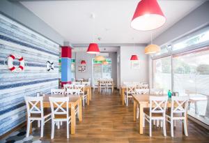 a restaurant with wooden tables and chairs and red lamps at Porto Marina in Krynica Morska