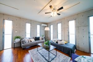 uma sala de estar com um sofá e uma ventoinha de tecto em EM Tree House em Uruma