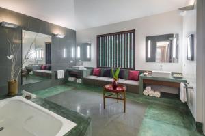 a bathroom with a tub and a couch and a sink at Purity at Lake Vembanad in Mararikulam