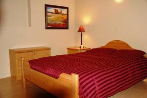 a bedroom with a bed with a red striped comforter at A Vacation Paradise at Quail Ridge B&B in Kelowna