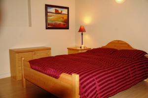 una camera da letto con un letto con un piumone a righe rosse di A Vacation Paradise at Quail Ridge B&B a Kelowna