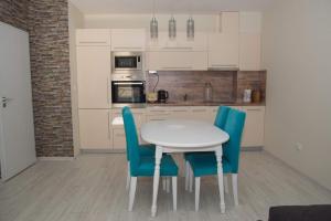 cocina con mesa blanca y sillas azules en Луксозен апартамент Свети Влас Вила Аристо, en Sveti Vlas