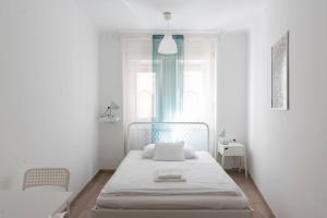 a white bedroom with a bed and a window at Vajda 15 Hostel Budapest in Budapest