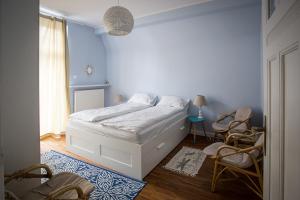 a bedroom with a white bed and two chairs at Apartament Winieckiego in Sopot