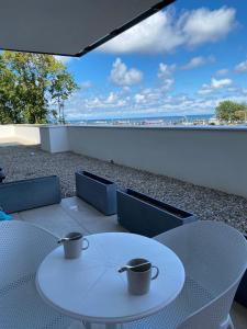 zwei Kaffeetassen auf einem weißen Tisch auf einem Balkon in der Unterkunft Aquamarina Prima Gold in Misdroy