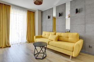 a living room with a yellow couch and a table at Angielska Grobla Apartinfo Apartments in Gdańsk