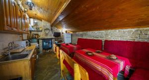 a living room with a red couch and a kitchen at Екокомплекс Катунище in Katunishte