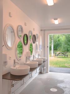Baño con 4 lavabos y espejos en la pared en Björkbackens Stugby i Vimmerby, en Vimmerby