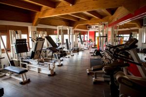 une salle de sport avec une rangée de tapis de course et de machines dans l'établissement Comano Cattoni Holiday, à Comano Terme