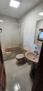 a bathroom with a toilet, sink, and tub at Apartamentos Portolux in Portomarin