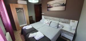 a hotel room with a large bed and a large mirror at Apartamentos Portolux in Portomarin