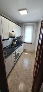 cocina con armarios blancos y fogones en Apartamentos Portolux, en Portomarín