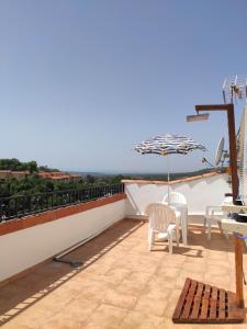 einen Balkon mit einem Tisch, Stühlen und einem Sonnenschirm in der Unterkunft Apartamentos La Relojera 2 in Jarandilla de la Vera