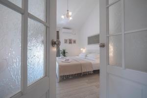 a white bedroom with a bed and a window at Marinero Apartments in Budva