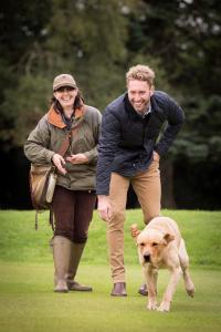 a man and a woman standing next to a dog at The Gleneagles Hotel in Auchterarder