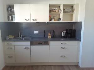 a kitchen with white cabinets and a sink at Freundliche Ferienwohnung mit großer Terasse in Aichstetten