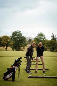 two men are playing golf on a golf course at The Gleneagles Hotel in Auchterarder