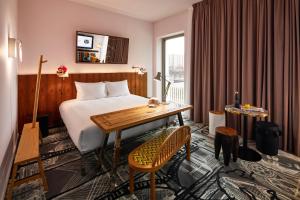 a hotel room with a bed and a desk and a window at Mama Shelter Luxembourg in Luxembourg