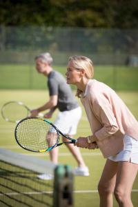 two women standing on a tennis court holding a racket at The Gleneagles Hotel in Auchterarder