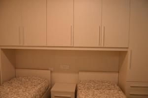 two beds in a room with white cabinets at COTTAGE ROSE in Bellagio