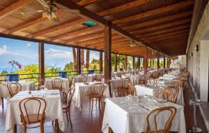 un salón de banquetes con mesas y sillas blancas en Marcaneto Hotel, en Scario