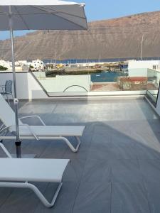 um pátio com um guarda-sol e cadeiras e uma piscina em La Pardela Exclusive Apartamentos em Caleta de Sebo
