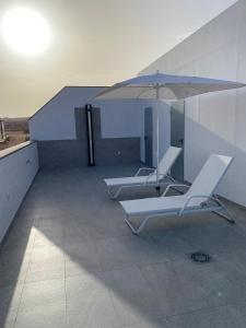 duas espreguiçadeiras e um guarda-sol num edifício em La Pardela Exclusive Apartamentos em Caleta de Sebo