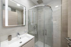 a bathroom with a shower and a sink and a mirror at Delux Apartments Sunset Beach in Promajna +39 photos