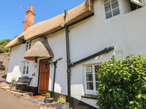 a white cottage with a thatched roof at Step a Side in Minehead