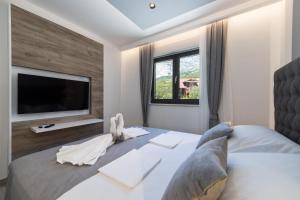 a bedroom with a large bed with a flat screen tv at Delux Apartments Sunset Beach in Promajna