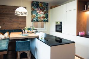 una cocina con armarios blancos y una barra con una silla azul en 423 - Penthouse apartment centrum Mayrhofen near ski area, en Mayrhofen