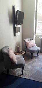 a living room with two chairs and a tv at Hotel Régina in Besançon