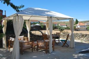 MuxagataCasa dos Primos的凉亭下配有椅子和桌子