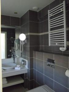 
a bathroom with a sink, toilet and mirror at Hôtel West End Promenade in Nice
