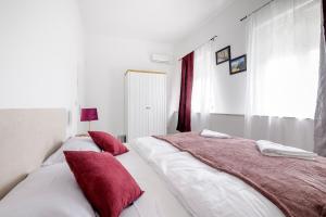 two beds in a white room with red pillows at Hostel Globo in Šibenik