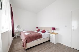 a white bedroom with a bed and a nightstand with a lamp at Hostel Globo in Šibenik