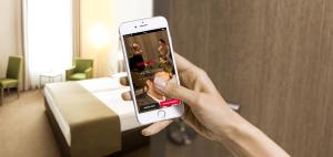 a person taking a picture of a hotel room with their cell phone at IntercityHotel Bonn City in Bonn