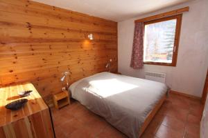sypialnia z łóżkiem i drewnianą ścianą w obiekcie Le Leyrier Hameau des Chazals Nevache Hautes Alpes w mieście Névache