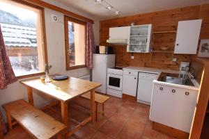 - une cuisine avec des appareils blancs et un mur en bois dans l'établissement Le Leyrier Hameau des Chazals Nevache Hautes Alpes, à Névache