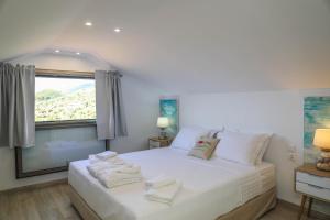 a bedroom with a large white bed with a window at Georgia Villas in Skiathos
