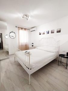 ein weißes Schlafzimmer mit einem weißen Bett und einem Fußboden in der Unterkunft La casa del pesciolino (into the lagoon) - The little fish house (into the lagoon) in Chioggia