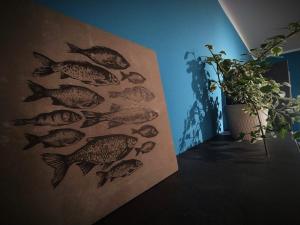 a painting of fish on a wall next to a plant at La casa del pesciolino (into the lagoon) - The little fish house (into the lagoon) in Chioggia