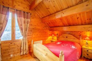 een slaapkamer van een blokhut met een rood bed bij Chalet Le Mélézin hameau des Chazals Nevache Hautes Alpes in Névache