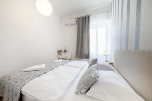 a bedroom with a bed with white sheets and a window at Hostel Globo in Šibenik