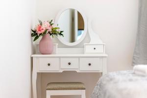 a white dressing table with a vase of flowers and a mirror at Hostel Globo in Šibenik