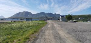 a dirt road with a house and a mountain in the background at Oppmyre Camping in Myre