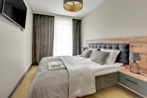 a bedroom with a large bed and a television at Angielska Grobla Apartinfo Apartments in Gdańsk